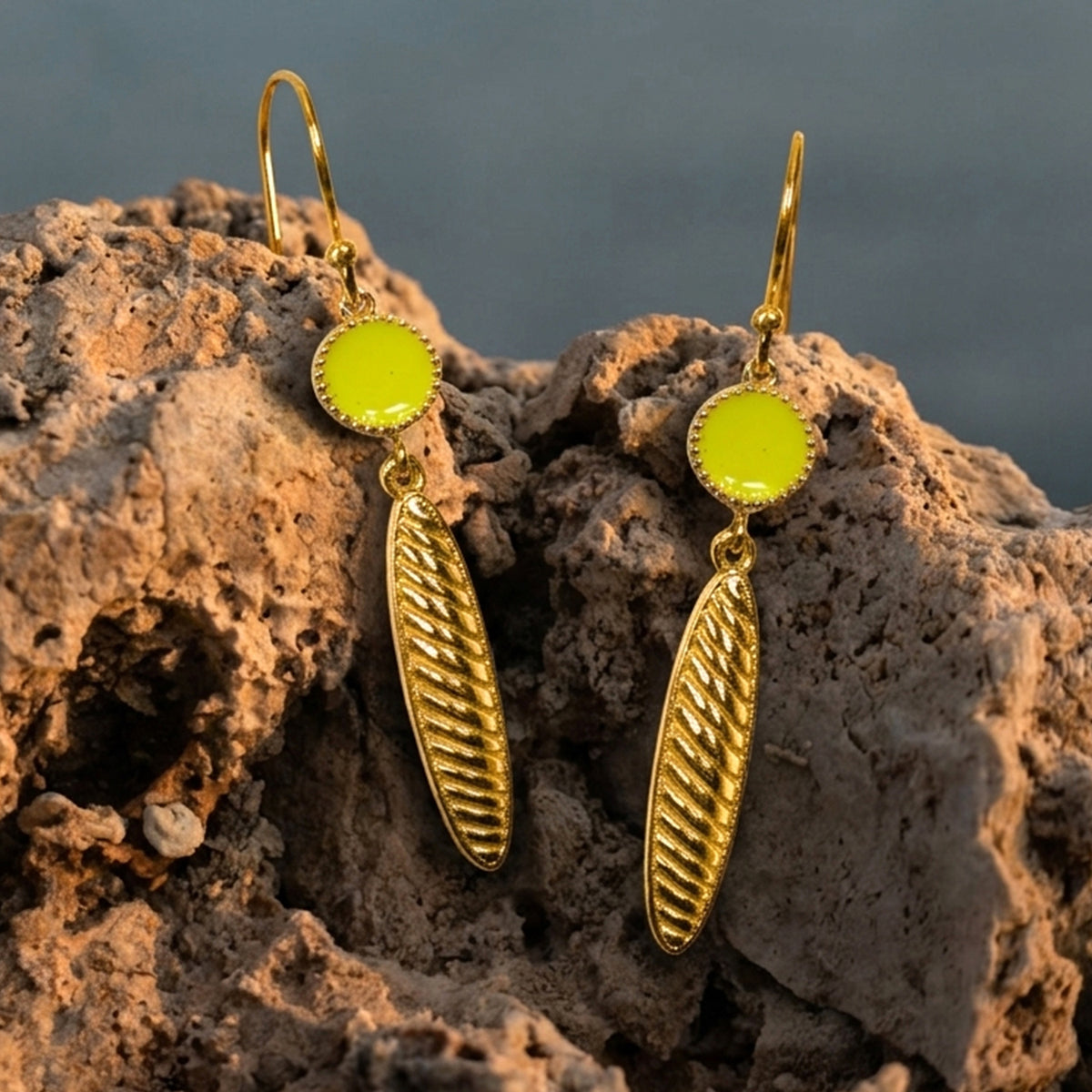 Deco Mosaic 18K gold-plated lime green enamel hook drop earrings styled on a brown rock with blurred blue-grey background — Studio Anivarya