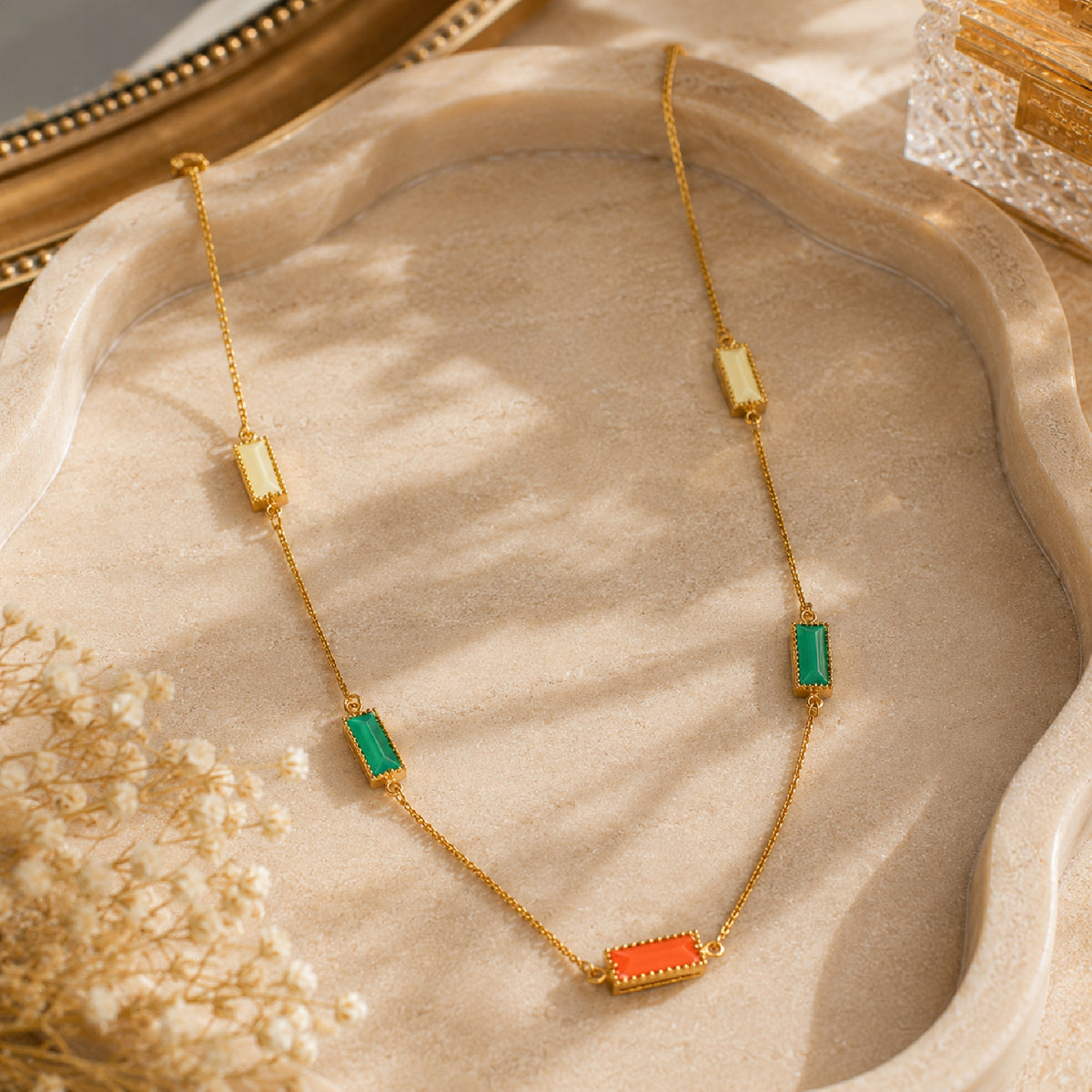 Deco Mosaic 18K gold-plated rectangular enamel pendant necklace in white, orange and green styled on a beige tray with dried flowers — Studio Anivarya