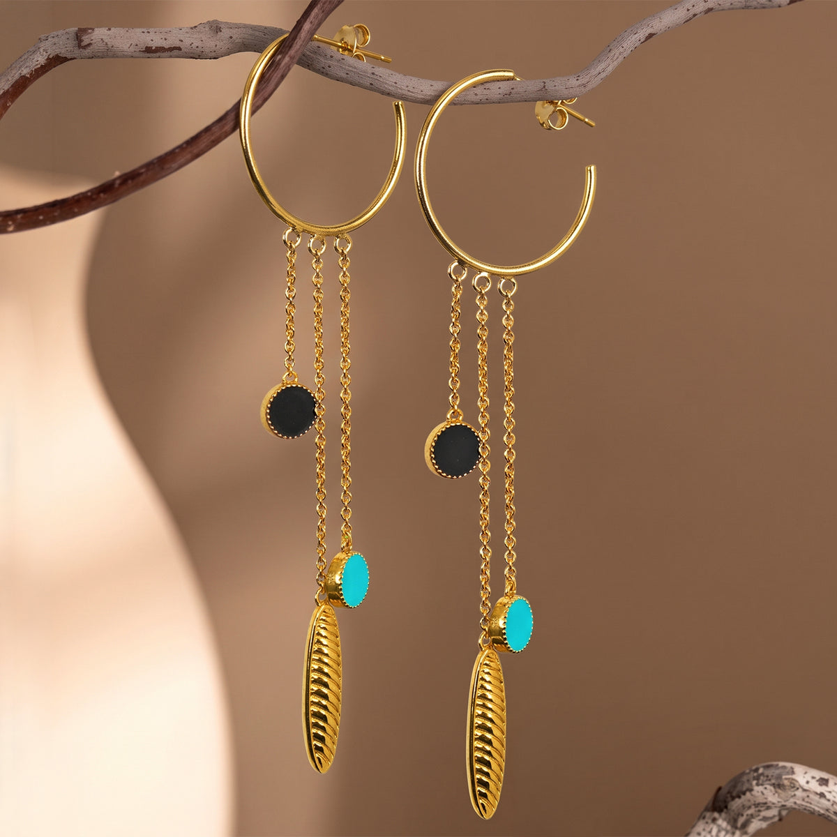 Deco Mosaic 18K gold-plated shoulder duster hoop earrings with blue and black enamel styled on a branch — mood shot — Studio Anivarya