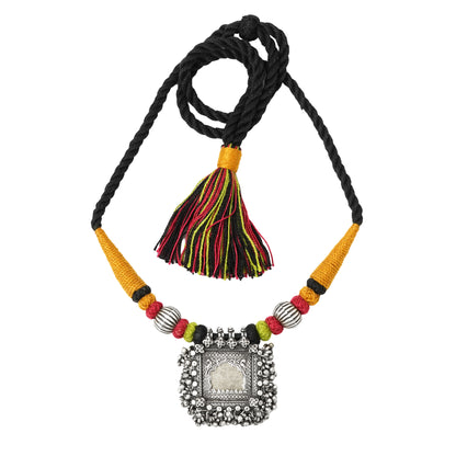 Taveez handcrafted silver necklace with stamped silver detailing, ochre, red and black Bandhai threadwork, gold-foiled glass pendant in silver frame, and tassel — white background — Studio Anivarya